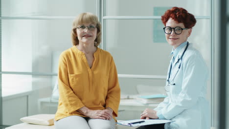 Portrait-of-Cheerful-Senior-Woman-and-Female-Doctor-in-Clinic